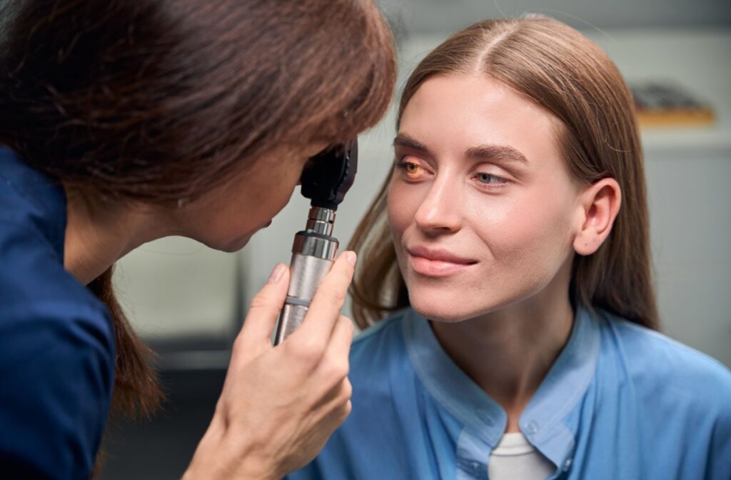 Optometrist examining a patient’s eye using a small handheld light during an eye exam.