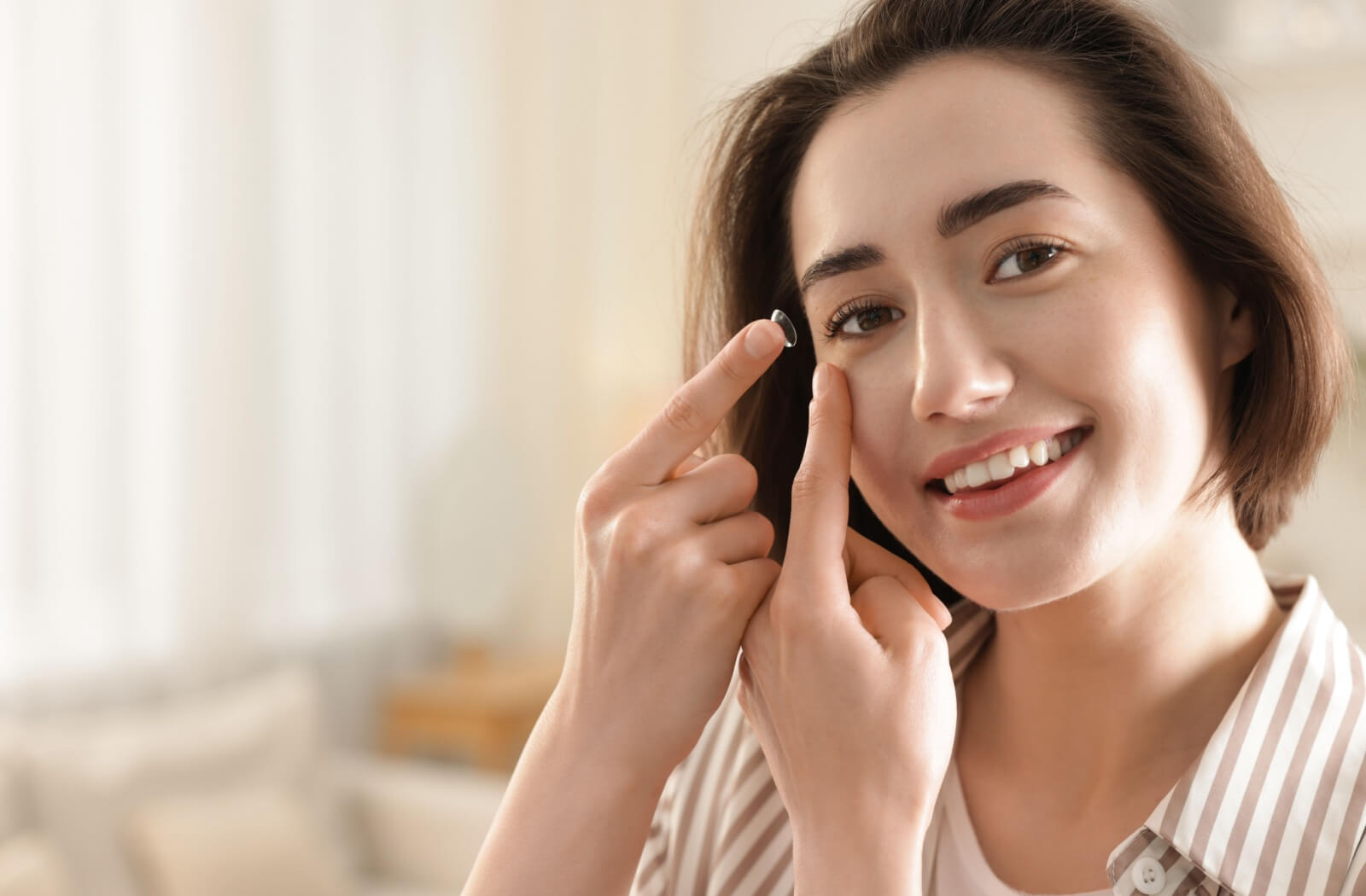 A person in a white coat holding a pair of eyeglasses in one hand and a contact lens case in the other.