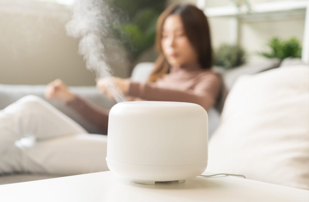 A white humidifier sitting on a desk with a women reading in the background
