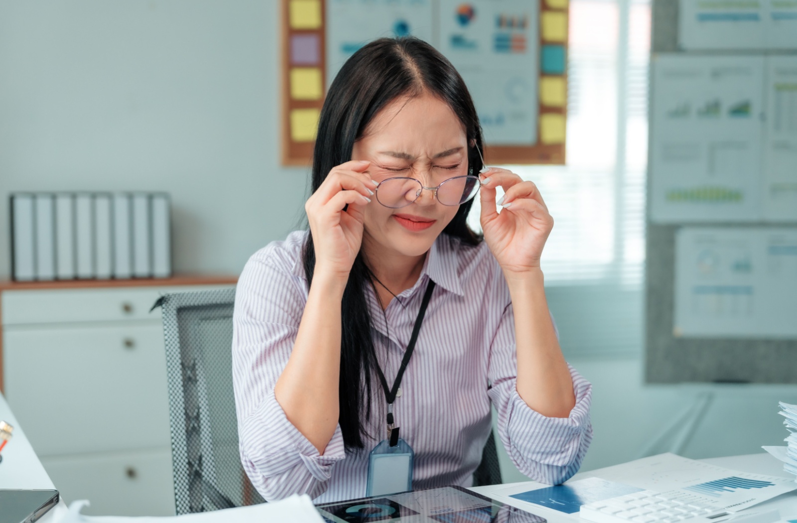 Person removing glasses to rub dry eyes
