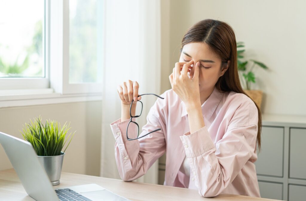 A person taking off their glasses to rub in between their eyes to alleviate some of the irritation from dry eye.