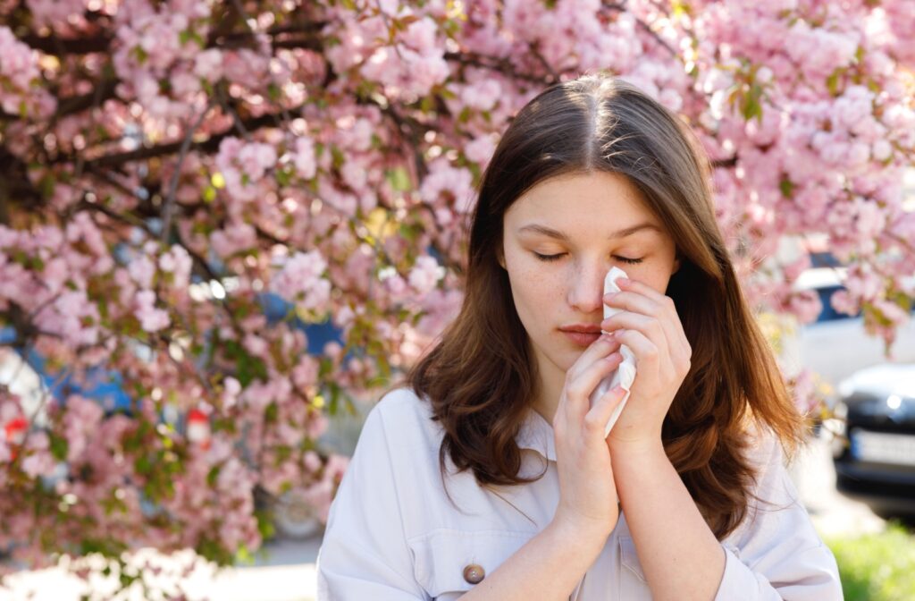 A person dapping their eye with a tissue as they experience eye allergies